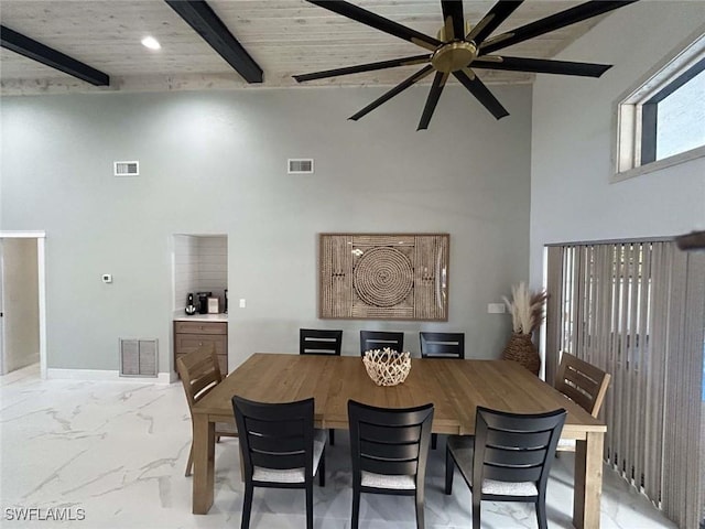 dining room featuring wood ceiling, a towering ceiling, beam ceiling, and ceiling fan