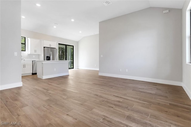 unfurnished living room with vaulted ceiling and light wood-type flooring