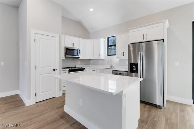 kitchen with a kitchen island, white cabinetry, sink, stainless steel appliances, and light hardwood / wood-style flooring