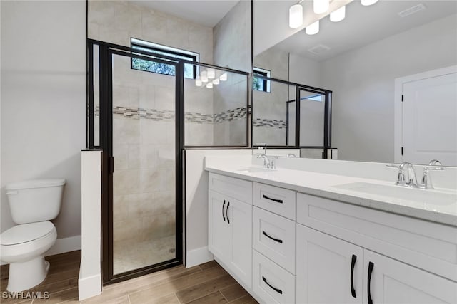 bathroom with a shower with door, vanity, and toilet