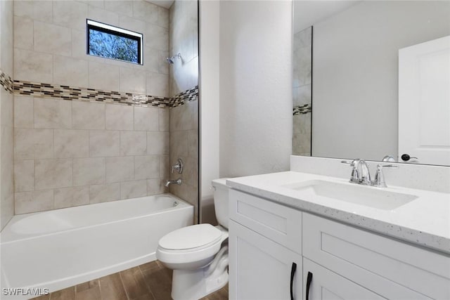 full bathroom with tiled shower / bath combo, wood-type flooring, vanity, and toilet