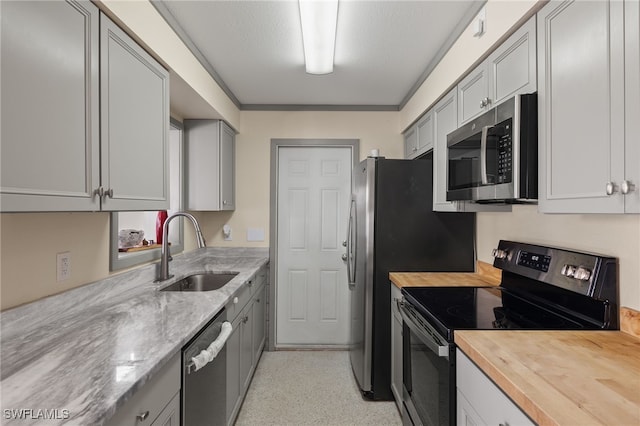 kitchen featuring stainless steel appliances, sink, gray cabinetry, and wooden counters