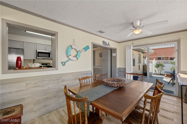 dining space with ceiling fan, ornamental molding, and light wood-type flooring