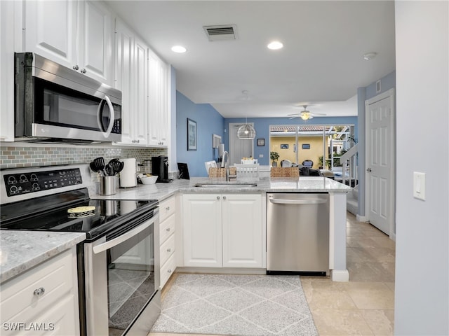 kitchen with sink, white cabinetry, backsplash, stainless steel appliances, and kitchen peninsula