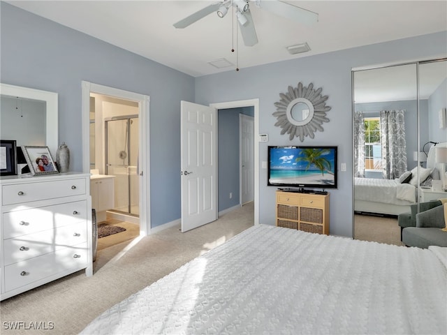 bedroom with ceiling fan, light colored carpet, ensuite bathroom, and a closet