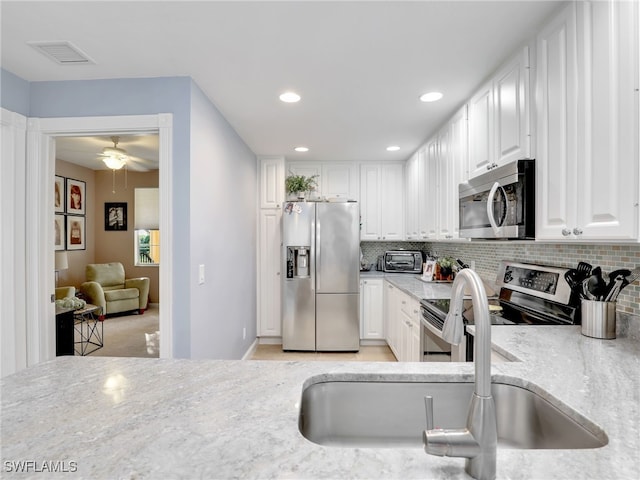 kitchen with white cabinetry, stainless steel appliances, sink, and backsplash