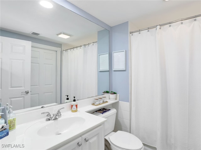 bathroom with vanity, tile walls, and toilet