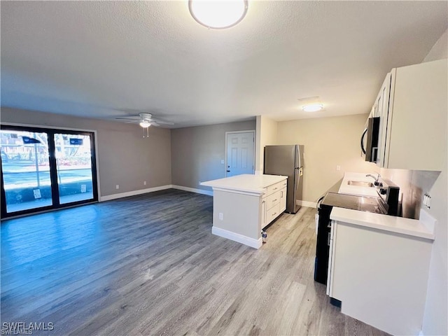 kitchen featuring sink, light hardwood / wood-style flooring, ceiling fan, stainless steel appliances, and white cabinets