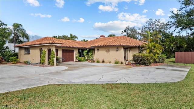 mediterranean / spanish-style home featuring a garage and a front lawn