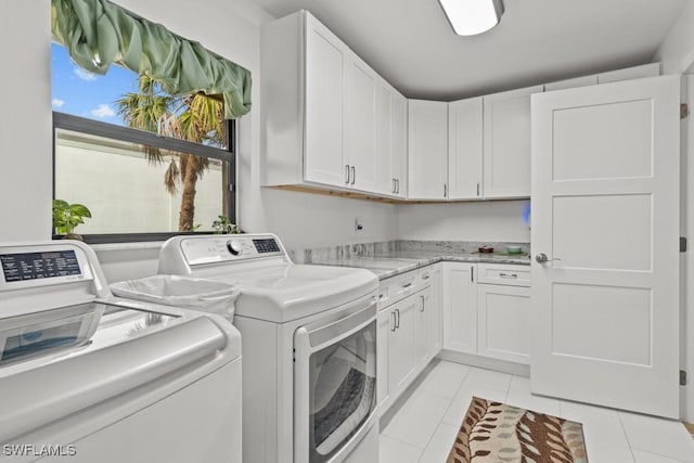 laundry area with separate washer and dryer, light tile patterned floors, and cabinets