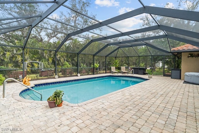 view of pool featuring a jacuzzi, a patio area, and glass enclosure