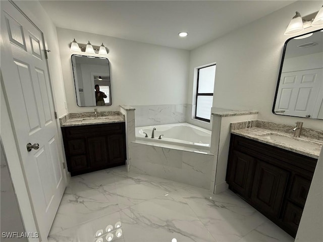 bathroom featuring a relaxing tiled tub and vanity