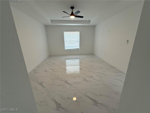 unfurnished room featuring ceiling fan and a tray ceiling