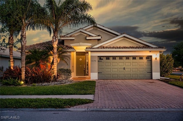 4176 Madison St, Ave Maria, FL 34142 - view of front facade featuring decorative driveway, a garage, and stucco siding