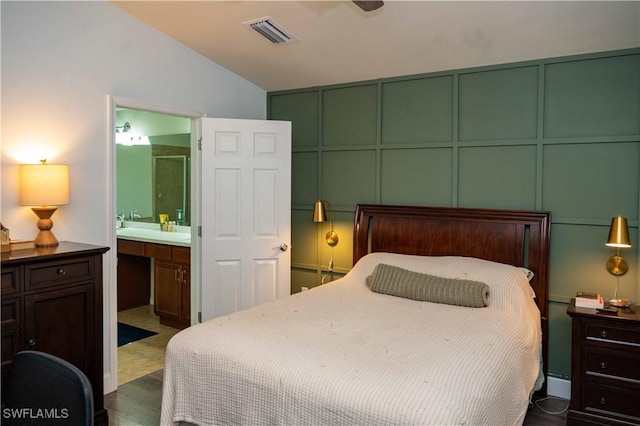 4176 Madison St, Ave Maria, FL 34142 - bedroom featuring lofted ceiling, dark wood-style floors, ensuite bathroom, and a decorative wall