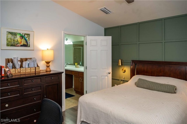 4176 Madison St, Ave Maria, FL 34142 - bedroom featuring vaulted ceiling, wood finished floors, ensuite bath, and a decorative wall