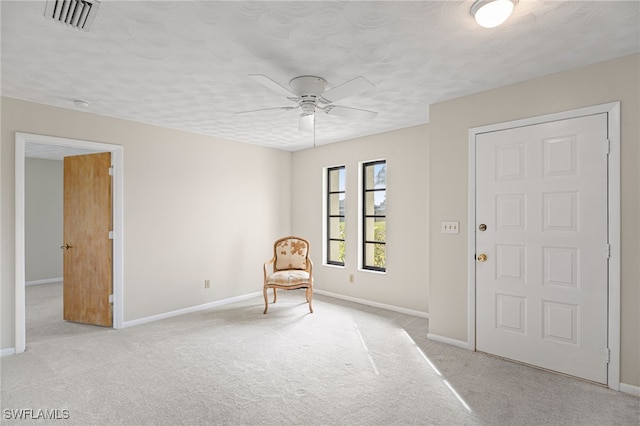 unfurnished room with ceiling fan, light carpet, and a textured ceiling