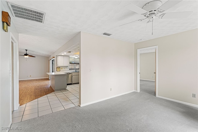 unfurnished living room with ceiling fan, lofted ceiling, light carpet, and a textured ceiling