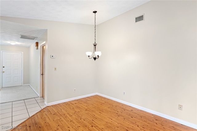 unfurnished dining area featuring an inviting chandelier and light hardwood / wood-style floors