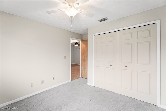 unfurnished bedroom featuring ceiling fan, light colored carpet, and a closet