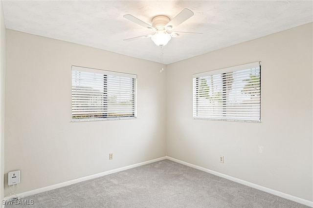 carpeted spare room with plenty of natural light and ceiling fan