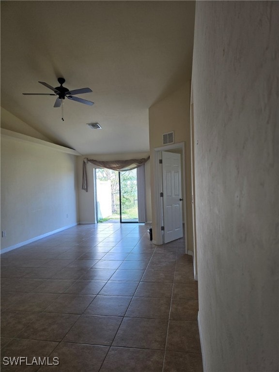 empty room with vaulted ceiling, dark tile patterned flooring, and ceiling fan