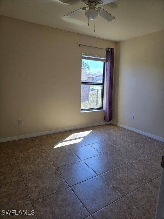 spare room with dark tile patterned floors and ceiling fan