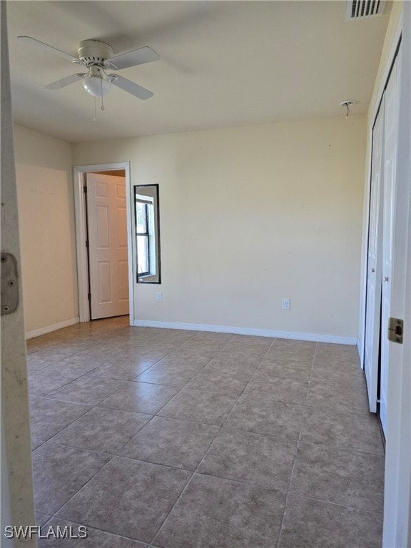 tiled spare room with ceiling fan