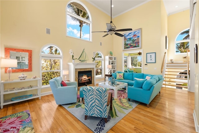 living room featuring crown molding, a wealth of natural light, ceiling fan, and light hardwood / wood-style floors