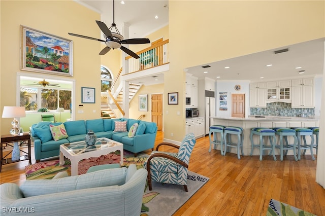 living room with crown molding, ceiling fan, and light wood-type flooring