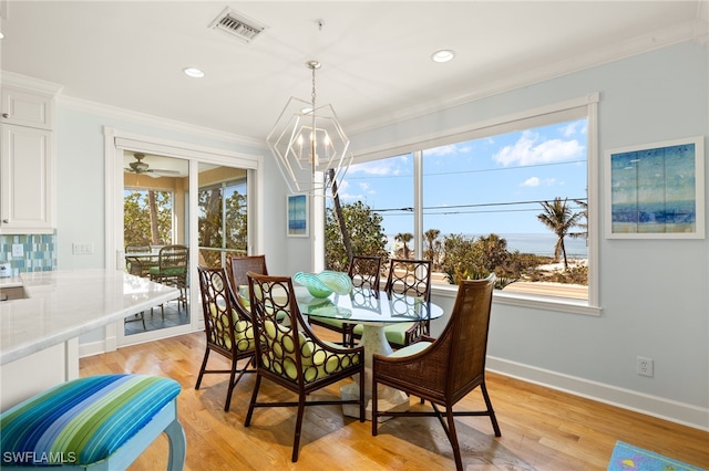 dining area featuring ornamental molding, a notable chandelier, and light wood-type flooring