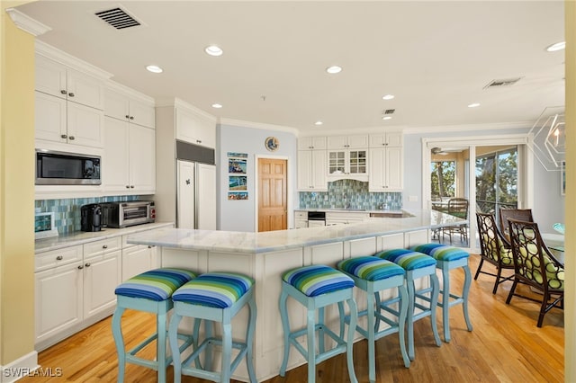 kitchen featuring ornamental molding, built in appliances, and white cabinets