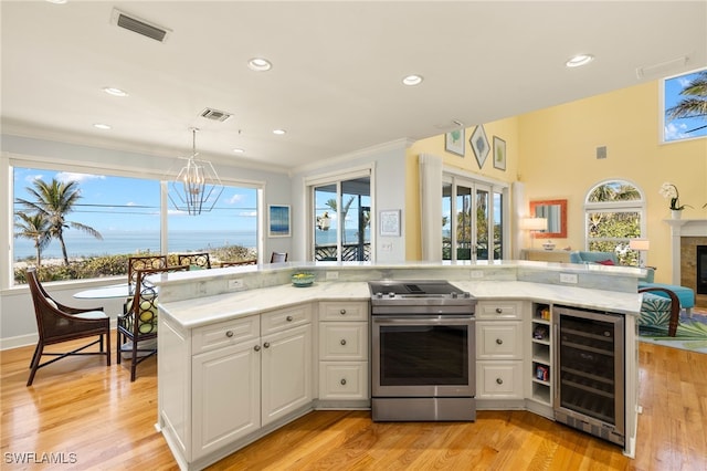 kitchen with white cabinets, wine cooler, hanging light fixtures, electric range, and light stone countertops