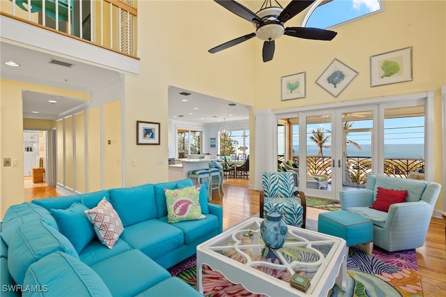 living room with french doors, a towering ceiling, ceiling fan, and light hardwood / wood-style floors