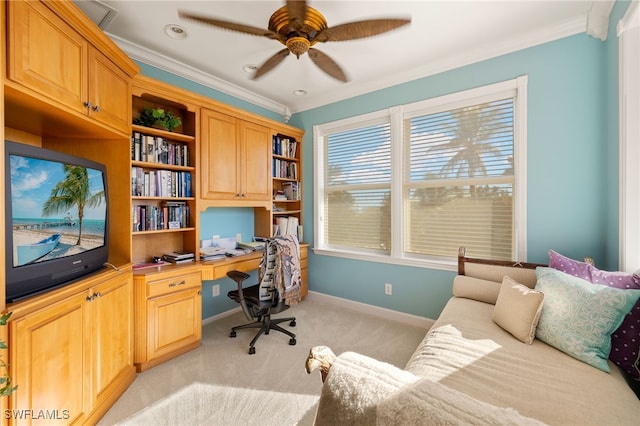 office space with ceiling fan, ornamental molding, built in desk, and light carpet