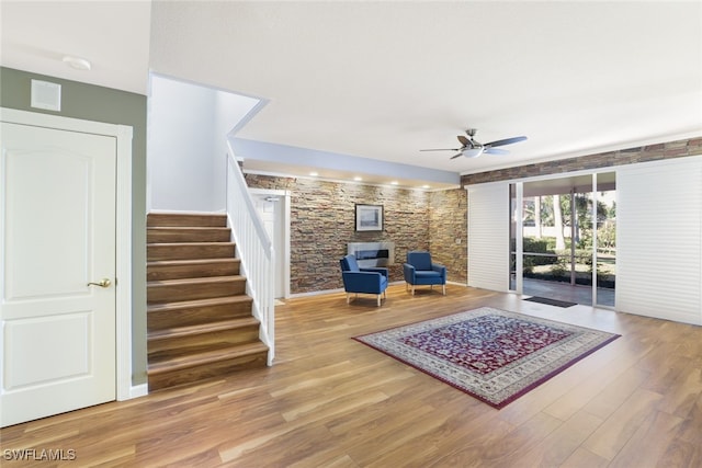 sitting room with stairs, visible vents, ceiling fan, and wood finished floors