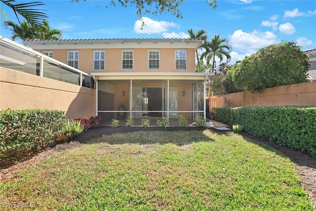 back of property with a lawn, fence, a sunroom, and stucco siding