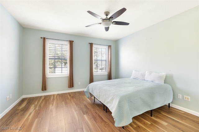 bedroom featuring a ceiling fan, baseboards, and wood finished floors