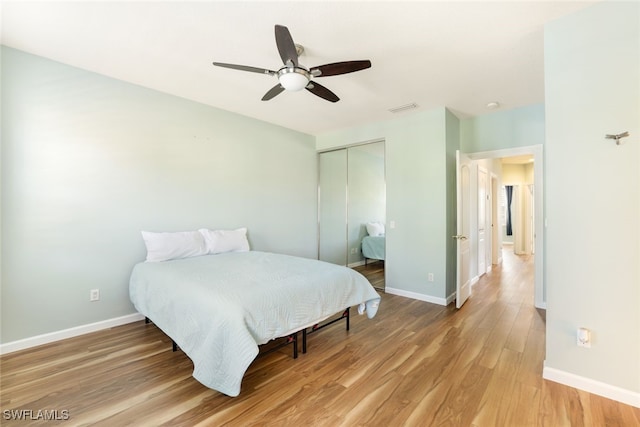 bedroom with light wood-style flooring, visible vents, baseboards, and a closet