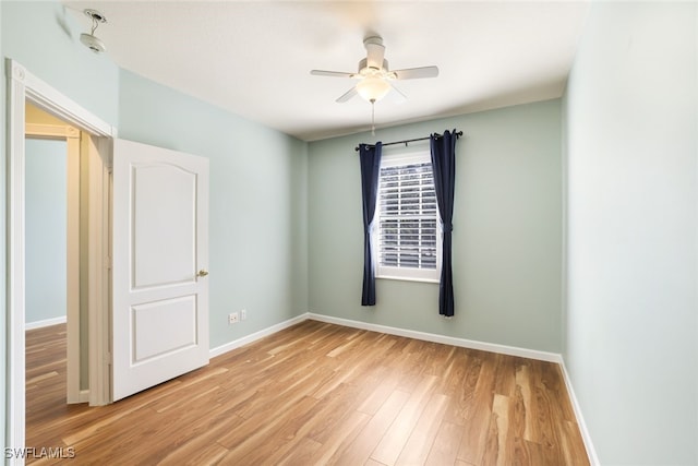 spare room featuring ceiling fan, light wood-style flooring, and baseboards