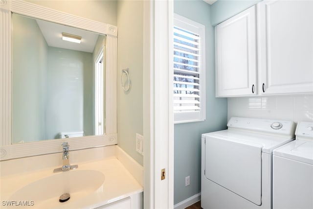 laundry area featuring cabinet space, a sink, washer and dryer, and a healthy amount of sunlight