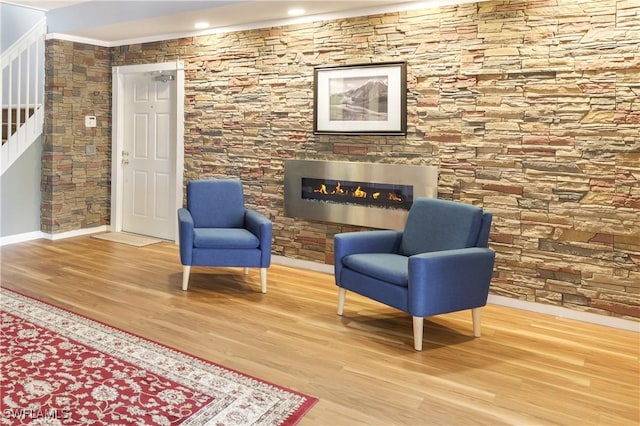 sitting room featuring stairs, a glass covered fireplace, baseboards, and wood finished floors