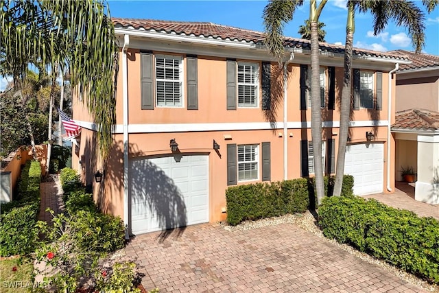 view of front of home featuring an attached garage, a tile roof, and stucco siding