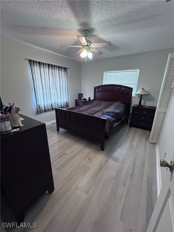 bedroom featuring a textured ceiling, light hardwood / wood-style floors, and ceiling fan