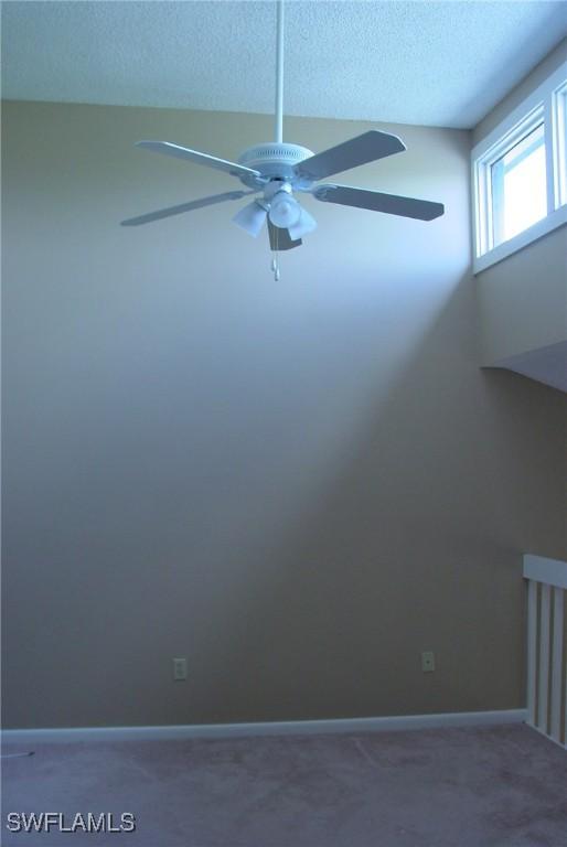 empty room featuring ceiling fan, a textured ceiling, and carpet flooring