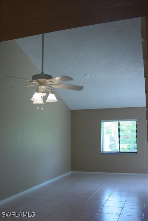 empty room featuring lofted ceiling, tile patterned flooring, and ceiling fan