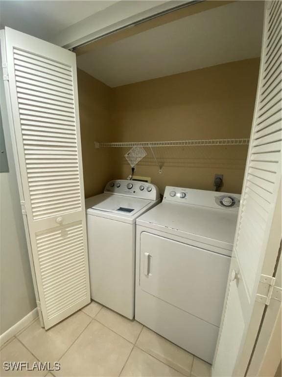 clothes washing area with independent washer and dryer and light tile patterned flooring