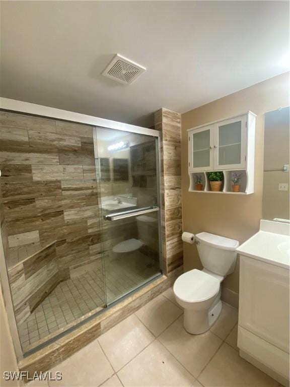 bathroom featuring vanity, a shower with door, tile patterned floors, and toilet