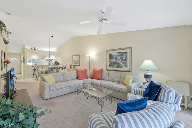 living room with ceiling fan with notable chandelier, light colored carpet, and vaulted ceiling