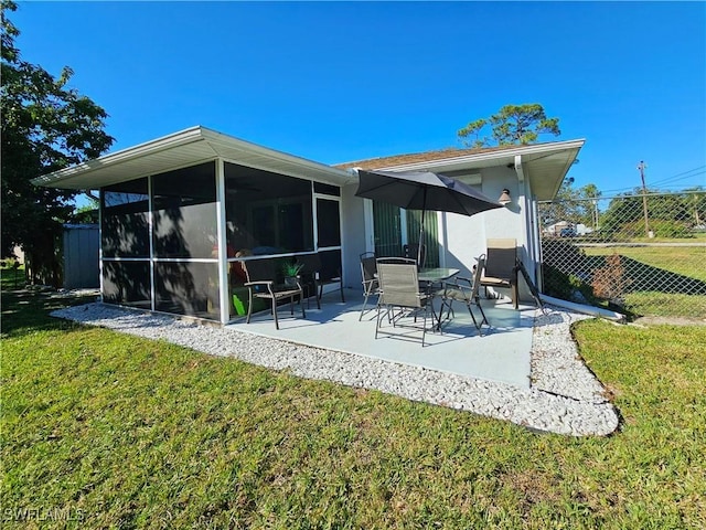 rear view of house featuring a yard, a sunroom, and a patio